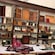 Wooden shelves filled with leather bound books, crafting tools and supplies, and a table with leather materials
